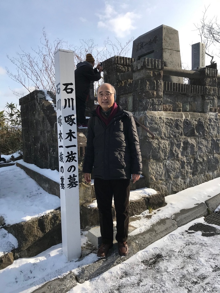 Masateru Ito en frente de la tumba de Takuboku